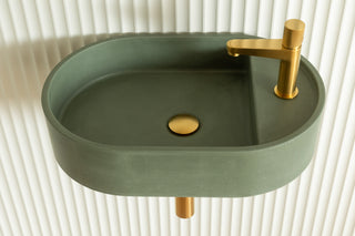 Green sink with gold faucet and drain on a white background